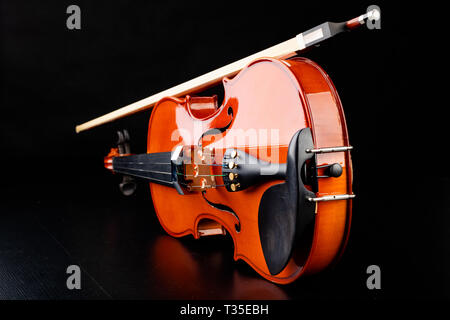 Beautiful new shiny violin on a dark table. Musical string instrument prepared for work. Dark background. Stock Photo