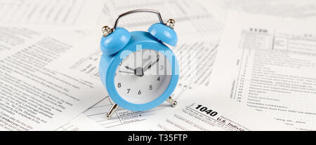 1040 Individual income tax return form with blue alarm clock. Concept of tax period in United States Stock Photo