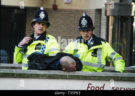 2 police officers arrest a drunk man in Reading town centre in the middle of the day Stock Photo