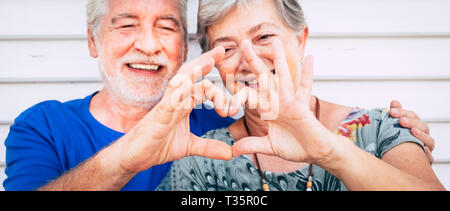70 year old senior couple playing forming heart with hands. Happiness and joy together forever concept for old people man and woman - romantic and rom Stock Photo