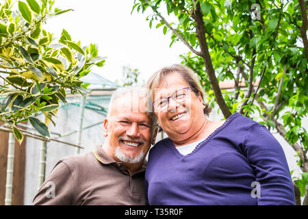 Portrait of cheerful happy senior aged couple smiling and having fun together in the garden looking at camera - retired lifestyle for nice caucasian p Stock Photo