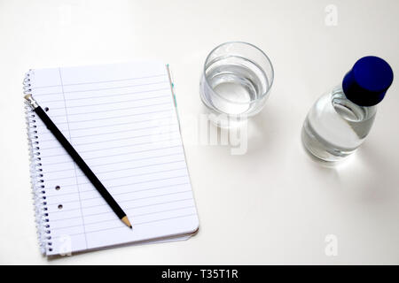 Notebook, pencil and glass of water on white background Stock Photo