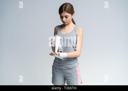 Young handsome caucasian woman wrapping her hands with a band, preparing herself for boxing training - sportive, healthy, fitness concept Stock Photo