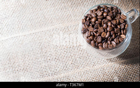 Artistic coffee themed background: a glass cup full of roasted b Stock Photo