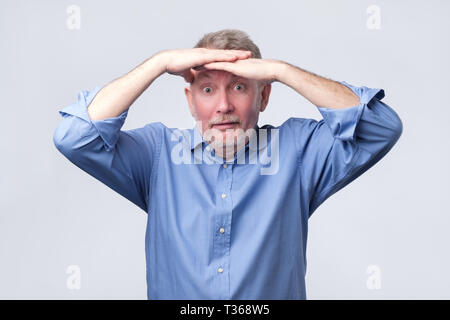 Senior man in blue shirt look far away. Studio shot. I need new glasses concept. Stock Photo