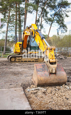 Yellow caterpillar tracked JCB JS130 LC heavy plant digger tracked excavator with bucket scoop at RHS Gardens, Wisley, Surrey, UK Stock Photo