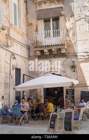 Cafe culture - locals and tourists dining at Cafe  on via Della Maestranza in Ortigia, Sicily, Italy Stock Photo