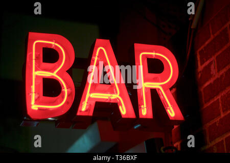 Neon red illuminated BAR sign captured with some color reflection on a brick wall in Kobe's Sannomiya area, Japan Stock Photo