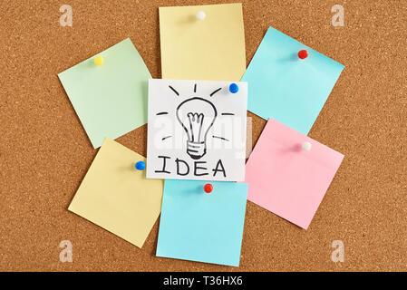 painted light bulb lamp with word idea and colored blank notes on cork board Stock Photo