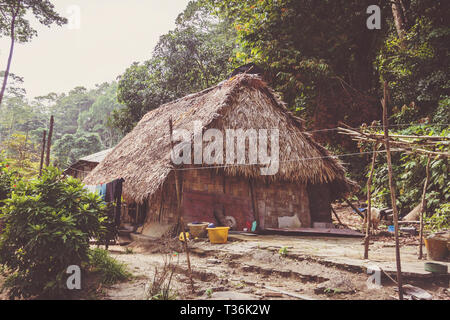 A little hut in in the tropical jungle. A rustic bamboo building with a thatched roof of a poor Indian family. Stock Photo