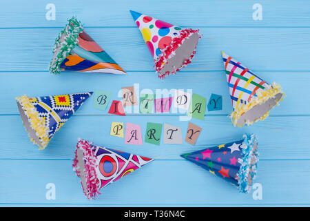 Birthday party composition with cardboard hats. Flat lay colorful party caps and inscription Birthday Party from multicolored letters. Stock Photo