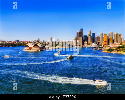Heavy maritime boat traffic on Sydney harbour in view of major city CBD landmarks seen from elevation of Harbour bridge on a bright sunny day. Stock Photo