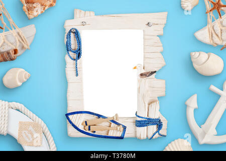 Summer sea travel photo frame on blue desk surrounded with shells, boat anchor, lifebelt. Stock Photo