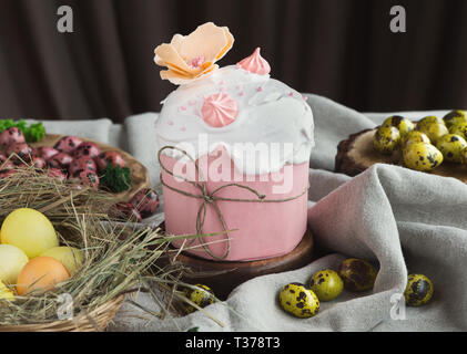 Traditional Easter sweet cake decorated with pink meringue and various coloured eggs on light background Stock Photo