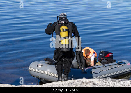 Republic of Karelia, Russia - August 20, 2015: Scuba diver standing near the boat checking equipment and preparing to dive. Stock Photo