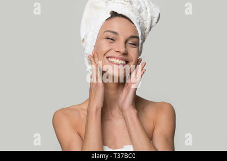 Smiling woman with towel on head touch clean healthy skin Stock Photo