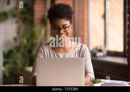 Happy mixed race woman student using laptop working studying indoor Stock Photo