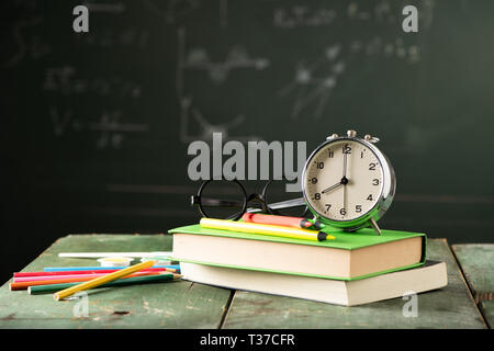 Back to school background with books and alarm clock over chalkboard ...