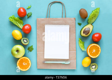 Healthy food background. Healthy food and paper bag vegetables and fruits on blue, copy space. Shopping list food supermarket concept. Stock Photo