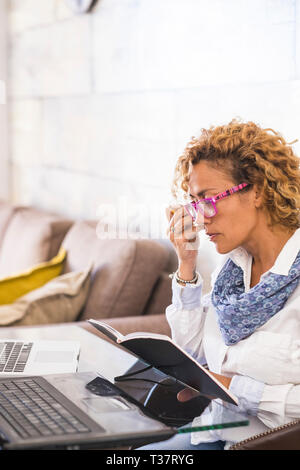 Beautiful caucasian young woman at home work or study with two personal laptop on the desk - people studying over 40 years of age concept - business w Stock Photo
