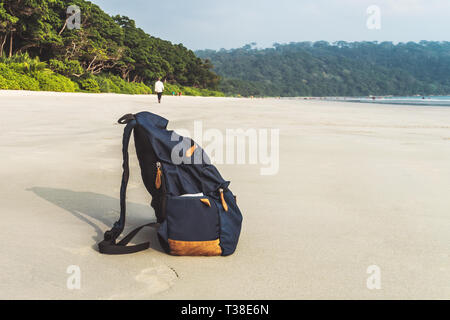 Travel Backpack on Summer Sea Beach. Holiday and Vacation Symbol. blue backpack thrown on white sand by the sea. Stock Photo