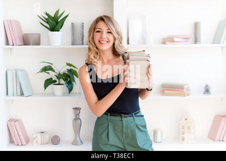 Female student holding books. Beautiful blonde girl keeps a stack of books and smiling. The concept of education, courses, examinations, homework Stock Photo