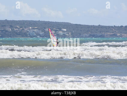 CAN PASTILLA, MALLORCA, SPAIN - APRIL 6, 2019: Surfers play in the green waves on a windy and sunny day on April 6, 2019 in Can Pastilla, Mallorca, Sp Stock Photo