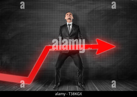 Standing businessman with red graph arrow Stock Photo - Alamy