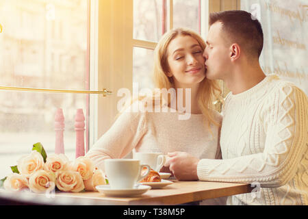 True love. Portrait of young couple have romantic lunch in cozy french restaurant. Man kissing his beloved girlfriend. Couple celebrating their specia Stock Photo