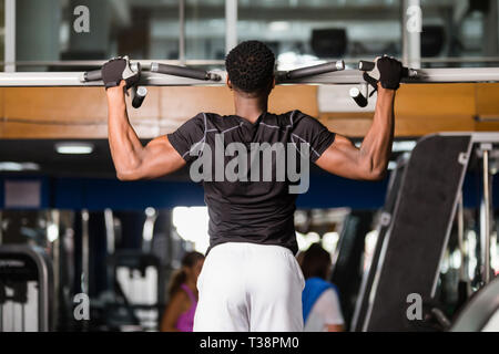 Black African American  young man doing pull up workout at the gym Stock Photo