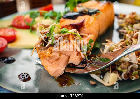 A piece of baked red fish with a side dish of sprouts and avocado salad. Macrobiotic food concept. Healthy food. Stock Photo