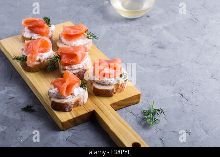 Party food, appetizer with salmon pate and smoked salmon on wooden cutting board, snack platter on gray background close-up, selective focus Stock Photo