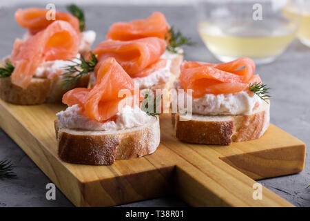 Party food, appetizer with salmon pate and smoked salmon on wooden cutting board, snack platter on gray background close-up, selective focus Stock Photo