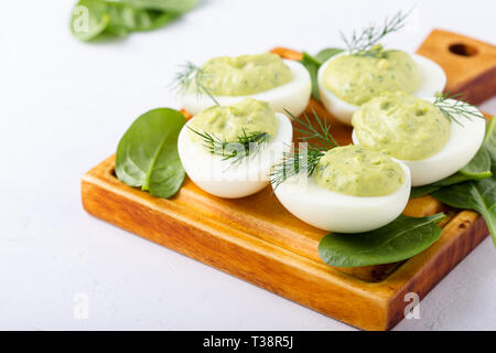 Deviled eggs with avocado and spinach on festive Easter table, close up, selective focus Stock Photo