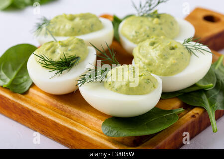 Deviled eggs with avocado and spinach on festive Easter table, close up, selective focus Stock Photo