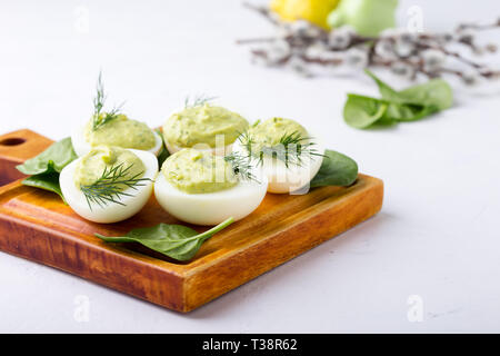 Deviled eggs with avocado and spinach on festive Easter table, close up, selective focus Stock Photo