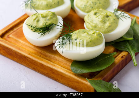 Deviled eggs with avocado and spinach on festive Easter table, close up, selective focus Stock Photo