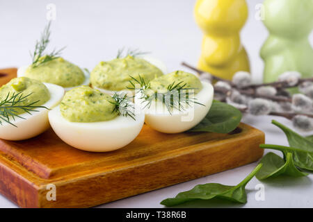 Deviled eggs with avocado and spinach on festive Easter table, close up, selective focus Stock Photo