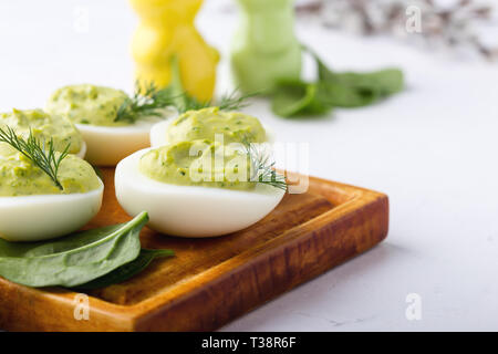 Deviled eggs with avocado and spinach on festive Easter table, close up, selective focus Stock Photo