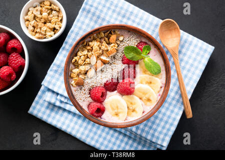 Tasty Smoothie Bowl With Berries, Granola, Chia Seeds On Blue Table Napkin, Black Background. Healthy Eating, Healthy lifestyle concept Stock Photo