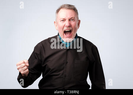 Angry shocked man in black shirt screaming, isolated on white background. Stock Photo
