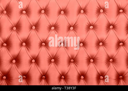 Coral toned pink leather capitone textile background, retro Chesterfield style checkered soft tufted fabric furniture decoration with buttons, close u Stock Photo