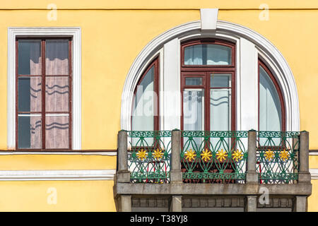 Semicircular window with a balcony against the background of the yellow wall. From a series of windows of St. Petersburg. Stock Photo