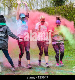 Three women runners being covered in paint on Macmillan cancer charity 5K color fun run. Stock Photo