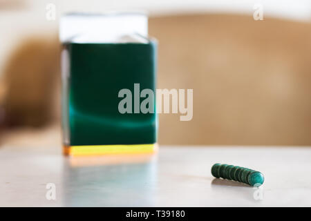 Spirulina pills in line on a table next to a box background. Stock Photo