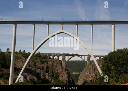 Container freight train crossing arch railroad bridge across Ulla river in Pontevedra, Spain Stock Photo