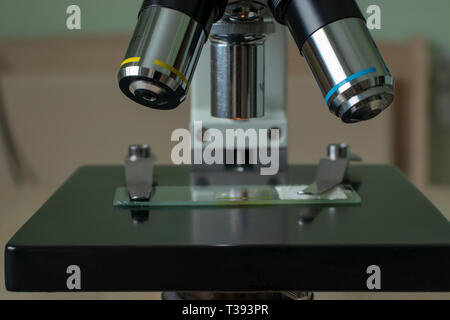 Microscope on the desk of the biologist with the micro-specimens, a scalpel and tweezers. Stock Photo