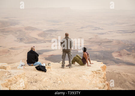 Mitzpe Ramon, Israel - 22 november, 2016: Three men watching the horizon on the edge of Ramon crater cliff at  Negev desert, Israel Stock Photo