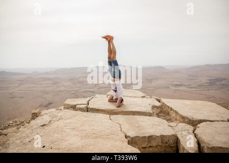 Mitzpe Ramon, Israel - 22 november, 2016: Man standing on his dead on the edge of Ramon crater cliff at  Negev desert, Israel Stock Photo