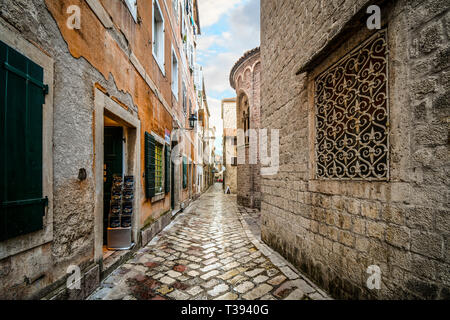 Small shops and cafes line a picturesque medieval street in the old town district of the coastal city of Kotor, Montenegro, on the Adriatic Coast. Stock Photo